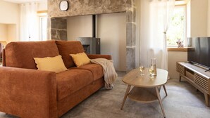 Una sala de estar con sofá, mesa de centro, televisor y chimenea de piedra.