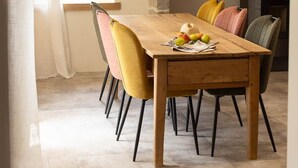 Un comedor con una mesa de madera, cuatro sillas y un reloj en la pared.