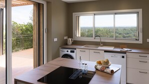 A modern kitchen with a large window, a built-in washing machine, and a sink.
