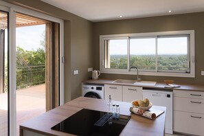 A modern kitchen with a large window, a built-in washing machine, and a sink.