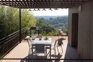 A wooden deck with a table and chairs, overlooking a forested landscape. - In the Shadow of First Names - André's Guesthouse (Miers)
