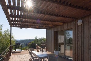A wooden deck with a table and chairs, overlooking a scenic landscape. - In the Shadow of First Names - André's Guesthouse (Miers)