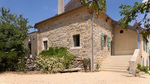 Un edificio de piedra con chimenea, una puerta de madera y una escalera de piedra que lleva a la entrada.