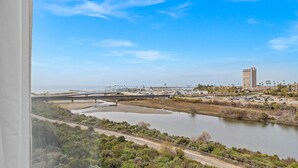 Une vue d’une zone côtière avec un pont, un immeuble de grande hauteur et une étendue d’eau.