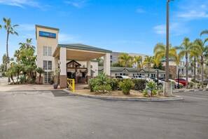 Ein Motel mit überdachtem Eingang, Palmen und Parkplatz.