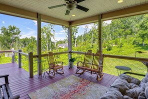 A covered porch with wooden flooring, rocking chairs, a small table, and a view of a green landscape. - Asheville Mountain Hideaway, 6 Mi to Dtwn (Asheville)
