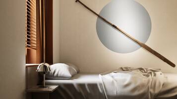 Ein Schlafzimmer mit einem Bett, einem Nachttisch, einer Lampe, einem Fenster mit Jalousien und einer runden Deckenleuchte.