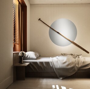 Une chambre à coucher comprenant un lit, une table de chevet, une lampe, une fenêtre avec des stores et un luminaire rond.
