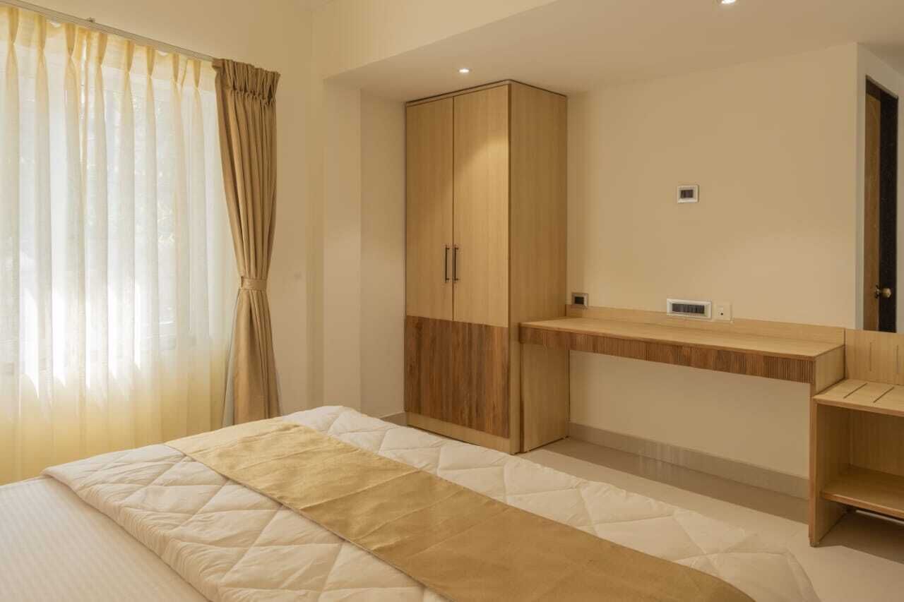 A bedroom with a bed, a wardrobe, a bedside table, and a window with curtains.