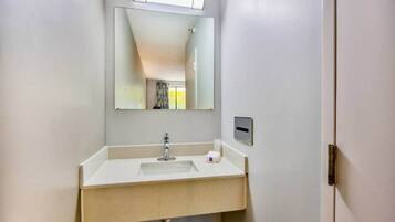 Un baño con lavamanos, espejo y puerta.