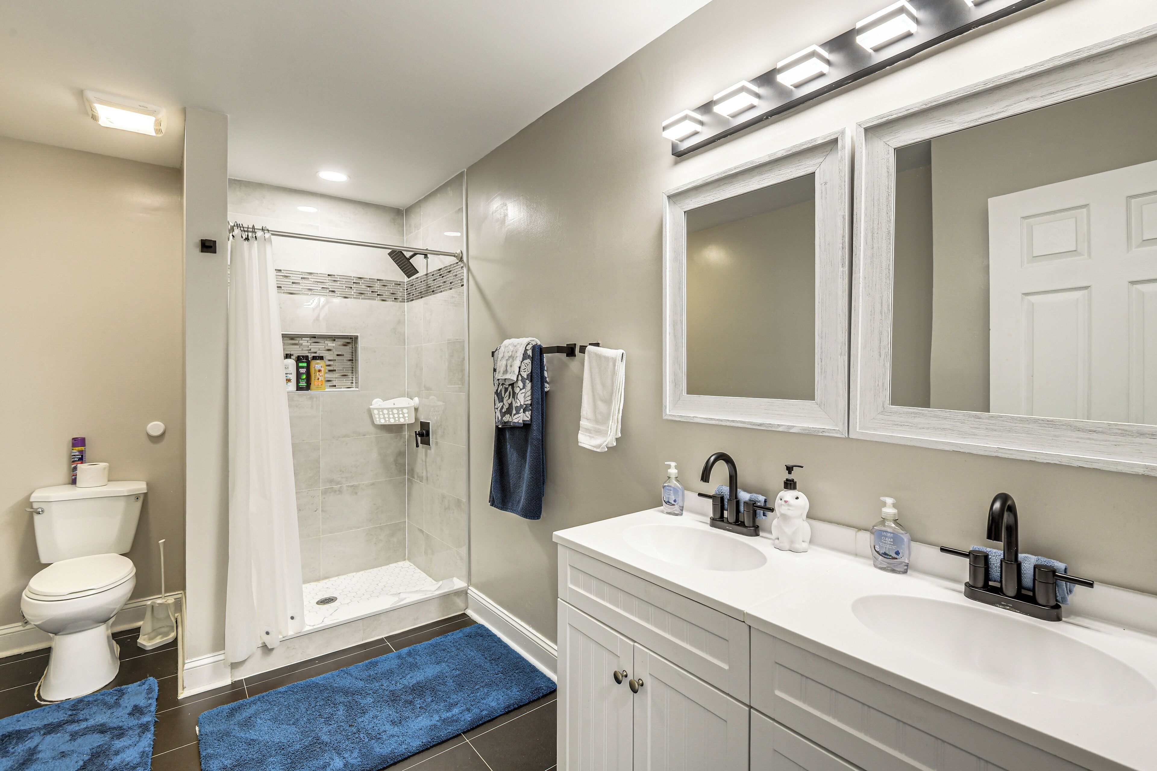 A bathroom with a shower, toilet, sink, and mirror.