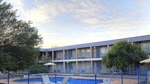 A hotel with a pool area, a fenced deck, and a multi-story building with balconies.