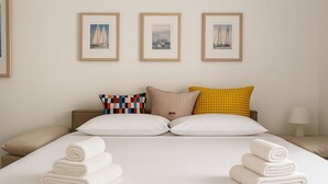 A hotel room with a large bed, two side tables, a nightstand, and three framed pictures on the wall.