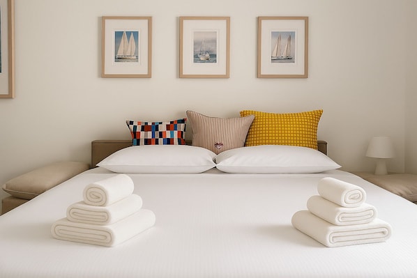 A hotel room with a large bed, two side tables, a nightstand, and three framed pictures on the wall.