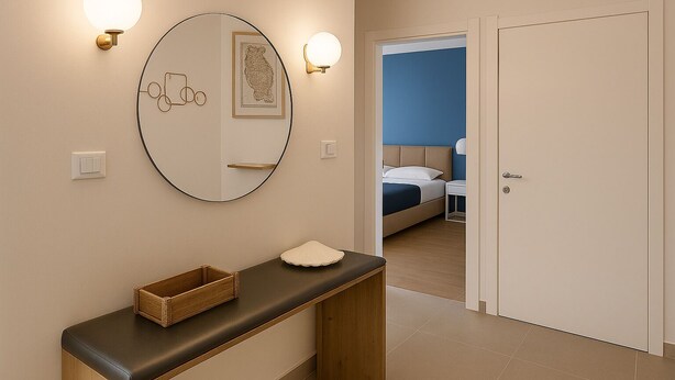 A hotel room with a bed, bedside table, and a mirror with wall sconces.