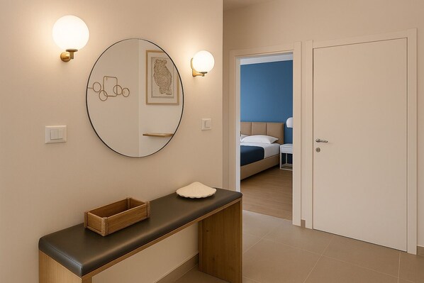 A hotel room with a bed, bedside table, and a mirror with wall sconces.
