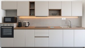 A modern kitchen with built-in appliances, a wooden countertop, and a stainless steel sink.