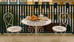 A table set with croissants, coffee, and juice, with chairs labeled 'Le Regole della Colazione.'