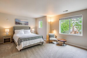 A bedroom with a bed, bedside lamps, a chair, a round table, a window with a view, and a painting on the wall. - 10 Min to Fairgrounds! Family Retreat in Puyallup (Puyallup)