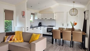 A modern kitchen with white cabinets, a dining area with a table and chairs, and a sofa with a yellow throw blanket. - Holiday Home in Dordrecht With Terrace (Dordrecht)