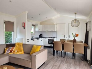 A modern kitchen with white cabinets, a dining area with a table and chairs, and a sofa with a yellow throw blanket. - Holiday Home in Dordrecht With Terrace (Dordrecht)