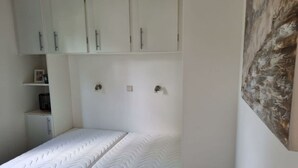A bedroom with a bed, white wardrobe, and a painting on the wall. - Holiday Home in Dordrecht With Terrace (Dordrecht)