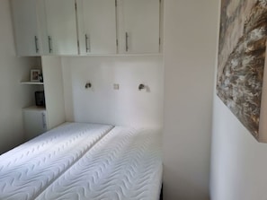 A bedroom with a bed, white wardrobe, and a painting on the wall. - Holiday Home in Dordrecht With Terrace (Dordrecht)