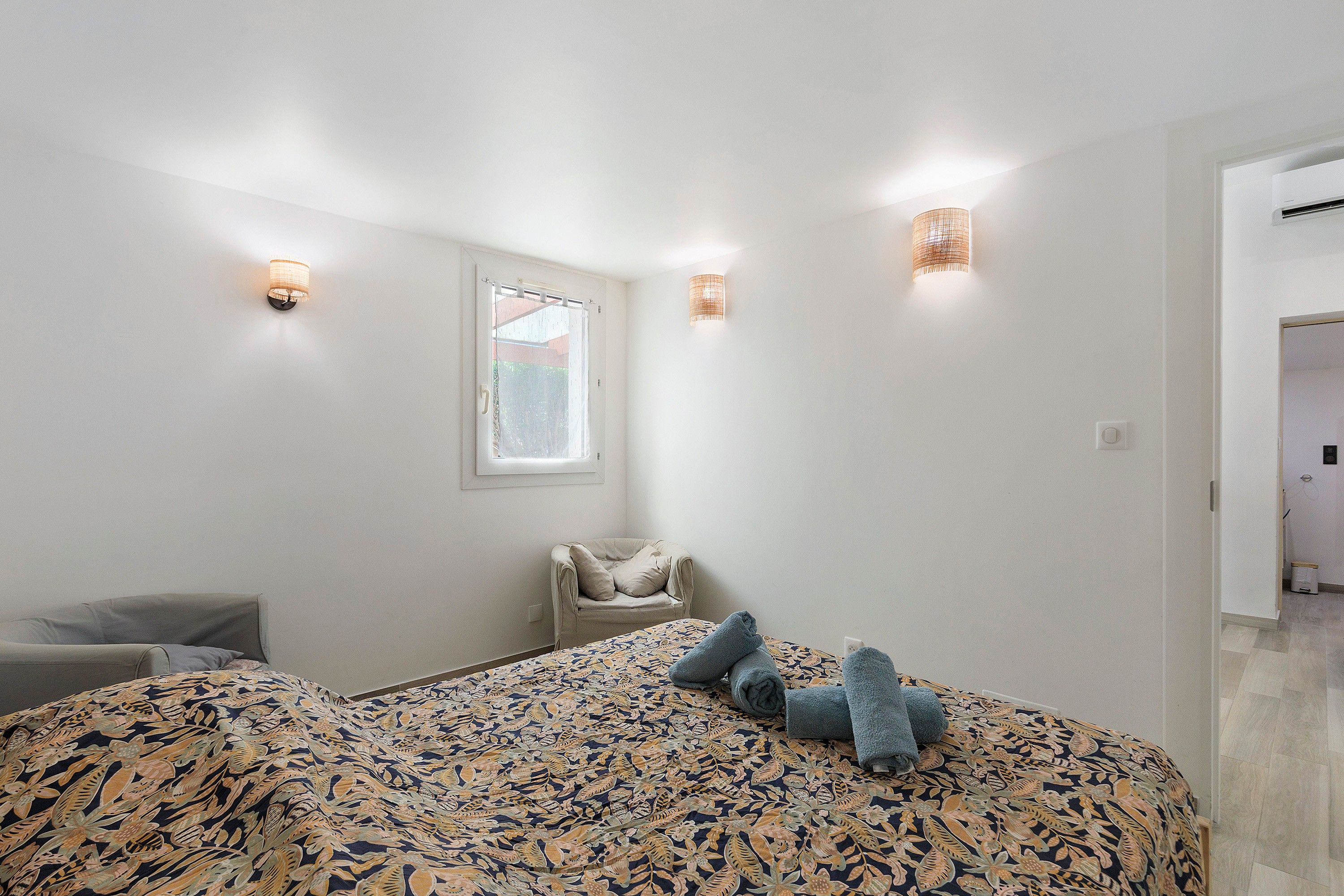 Une chambre à coucher avec un lit, une chaise et une fenêtre.