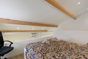 A bedroom with a bed, a chair, a desk, and a ceiling with wooden beams. - Le patio du soleil: pool, tennis, A/C, private terrace, near beaches (Vic-la-Gardiole)
