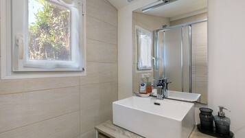 Ein Badezimmer mit einem weißen Waschbecken, einem Spiegel und einem Fenster.