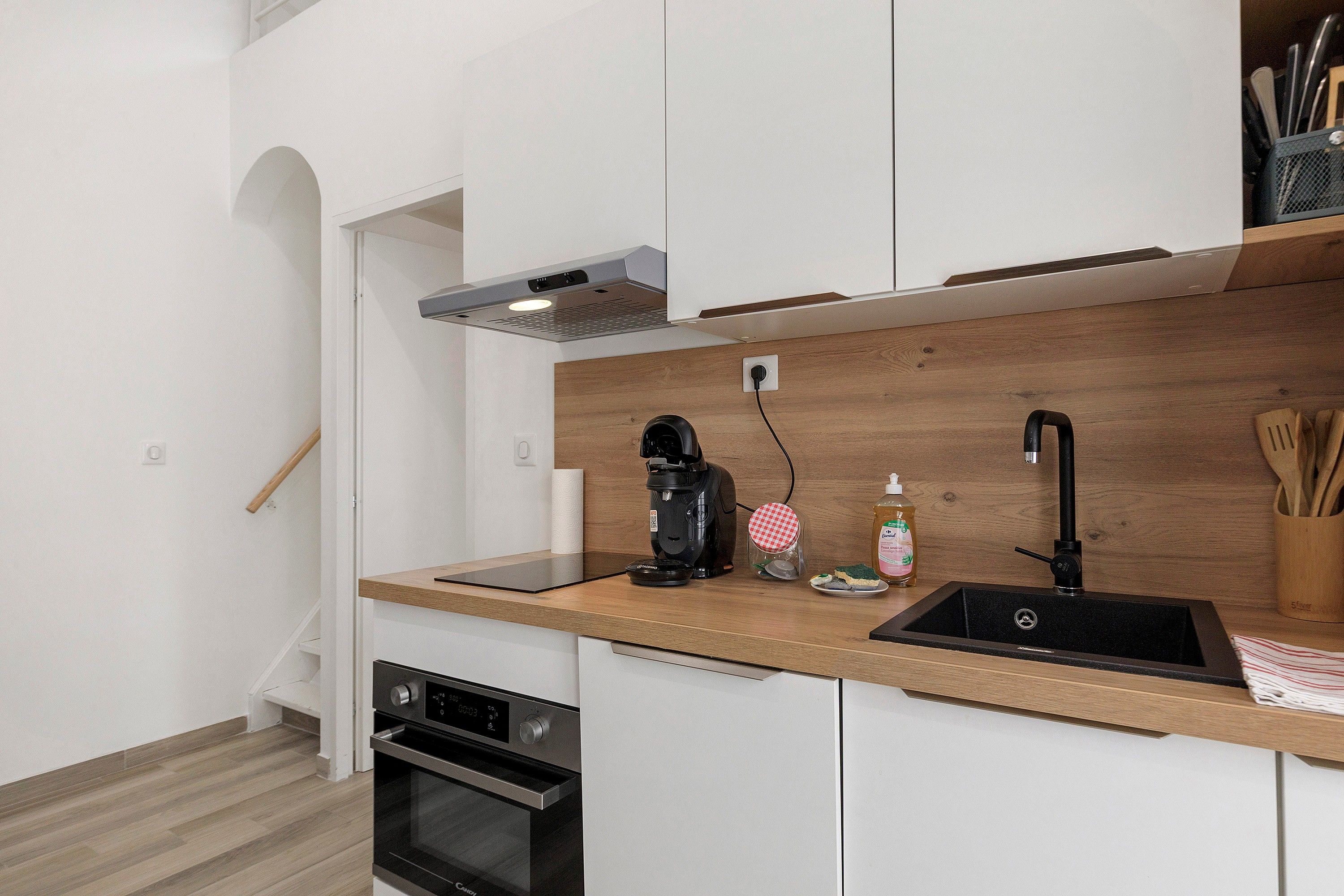 Une cuisine moderne dotée d’un four encastré, d’une machine à café, d’un évier et d’un plan de travail en bois.