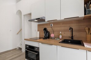 A modern kitchen with a built-in oven, a coffee maker, a sink, and a wooden countertop. - Le patio du soleil: pool, tennis, A/C, private terrace, near beaches (Vic-la-Gardiole)
