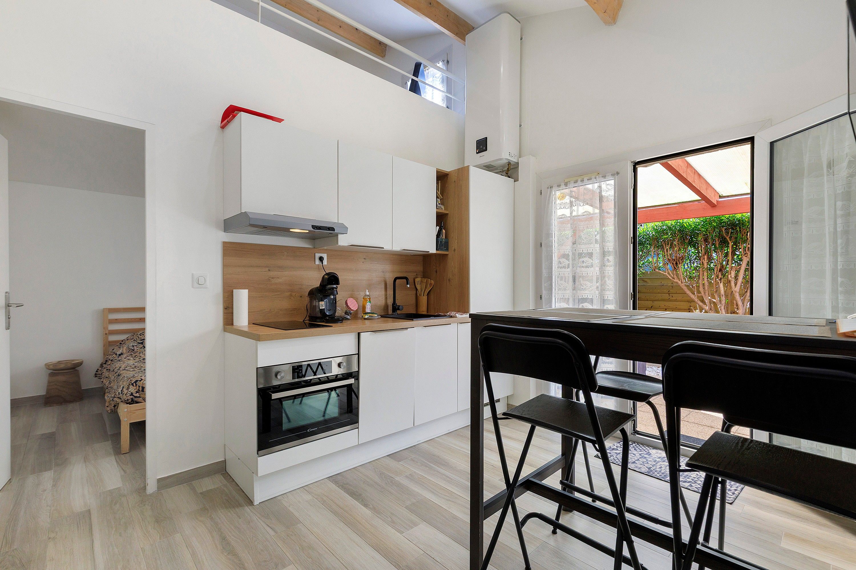 Una cucina moderna con mobili bianchi, forno integrato e macchina da caffè.