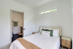 Ein Schlafzimmer mit einem Bett, einem Nachttisch, einem Fenster und einer Tür zu einem Badezimmer.