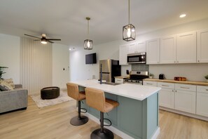 Eine moderne Küche mit einer Kochinsel, weißen Schränken und einem Deckenventilator.