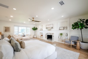 A spacious bedroom with a large bed, a fireplace, and a seating area with a chair and a table. - LUX Designer Oceanfront Estate in Long Beach - 4 Master Suites, Backyard Oasis (Long Beach)