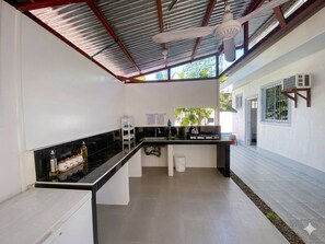 A kitchen with a black countertop, white cabinets, a gas stove, and a ceiling fan.