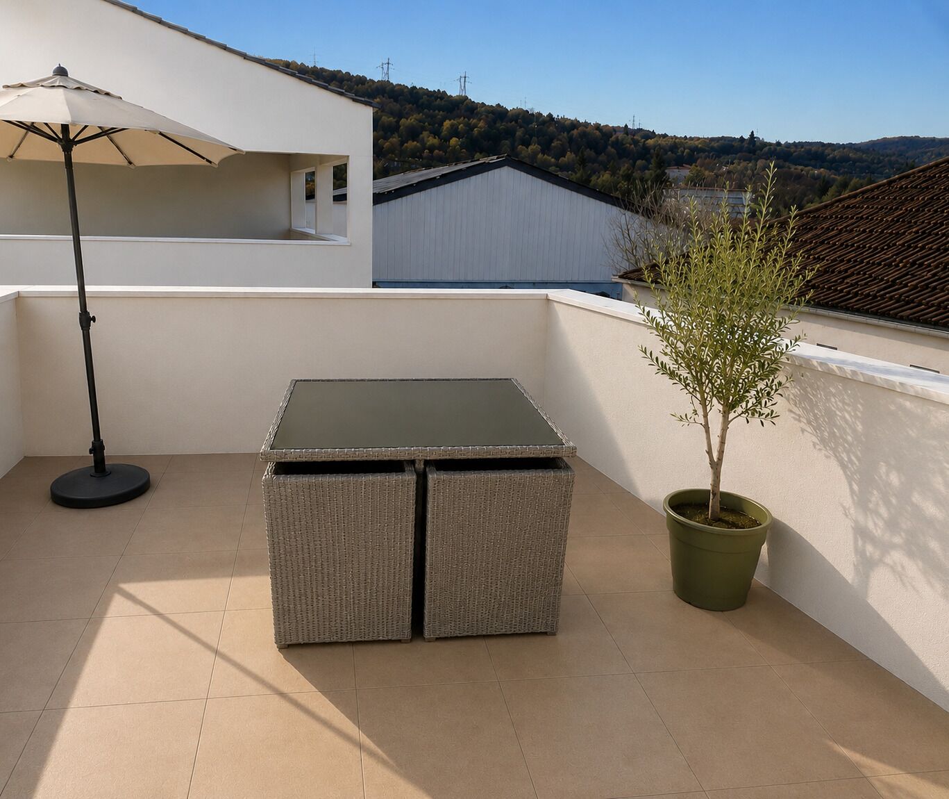 Een balkon met een tafel, stoelen, een plant in pot en een vloerlamp.