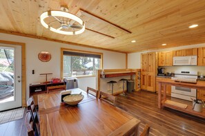 Ein Holzinterieur mit einem Esstisch, Stühlen, einer Mikrowelle und einem Herd.