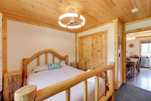 Ein Zimmer mit Holzrahmen, das ein Bett, eine Holztür und einen Essbereich mit Tisch und Stühlen bietet.