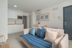 Ein modernes Wohnzimmer mit einer Couch, einem kleinen Tisch und einer Küchenzeile im Hintergrund.