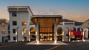 A hotel entrance with a covered walkway, arched windows, and a sign above the entrance.