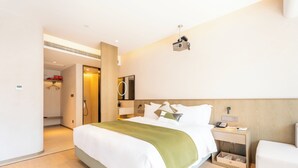 A hotel room with a bed, bedside table, and a mirror.