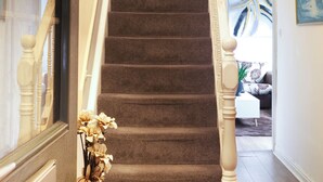 A staircase with carpeted steps, wooden balusters, and a red vase with dried flowers. - Double Room perfect for contractors and Professionals (West Midlands)