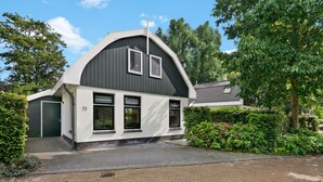 Ein modernes, zweistöckiges Haus mit grauem Dach, weißen Wänden und der Hausnummer 79.