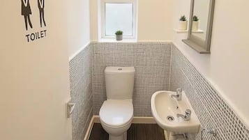 A small, modern bathroom with a toilet, sink, and a window.