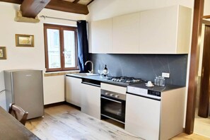A compact kitchen with a built-in oven, a gas stove, and a small refrigerator. - Apartment Camilla, Pesaro (Pesaro)