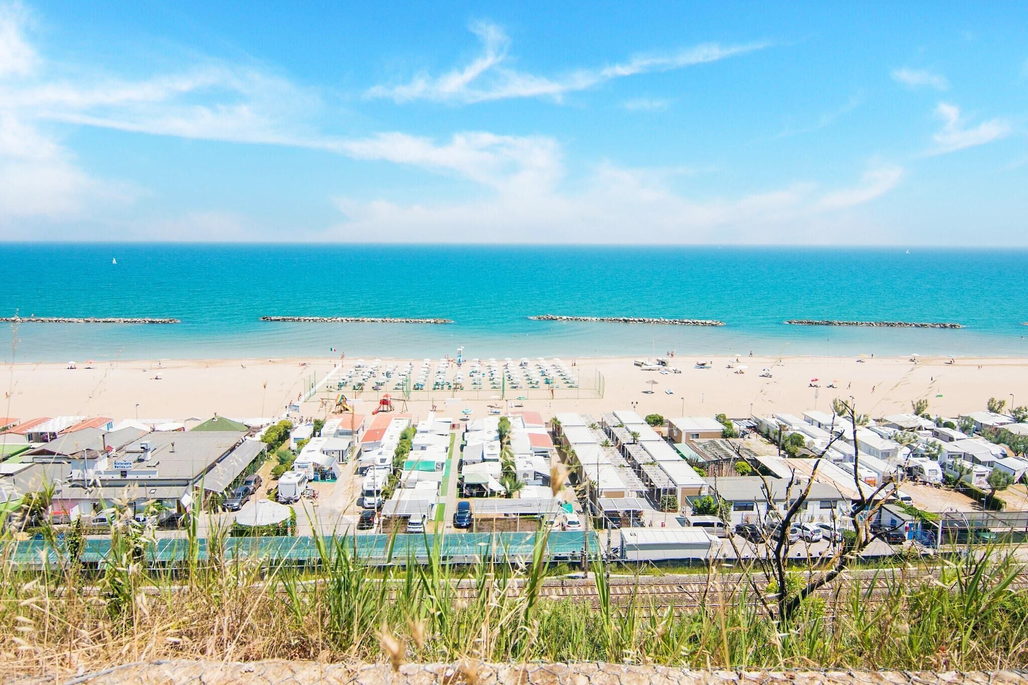 A beachside caravan park with rows of caravans, a sandy beach, and the sea in the background.