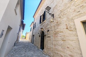 A narrow cobblestone street flanked by historic buildings with stone facades and arched doorways. - Apartment Camilla, Pesaro (Pesaro)