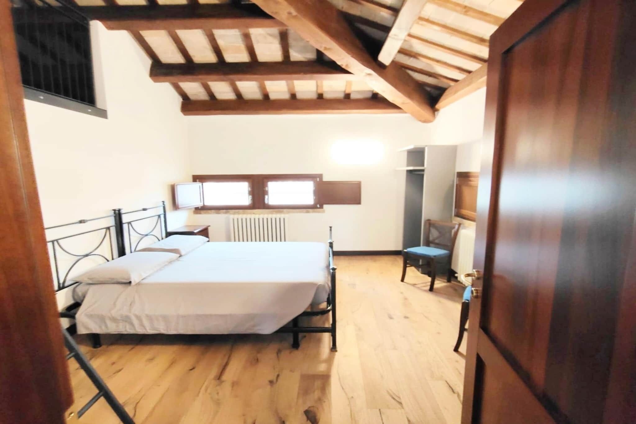 A bedroom with a bed, wooden floor, a radiator, and a window.